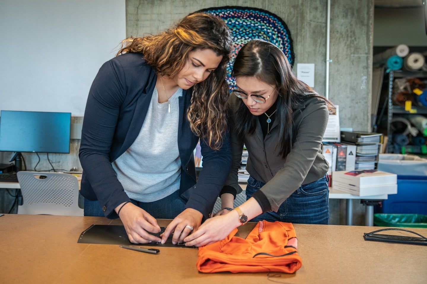 Two students work on a piece of clothing