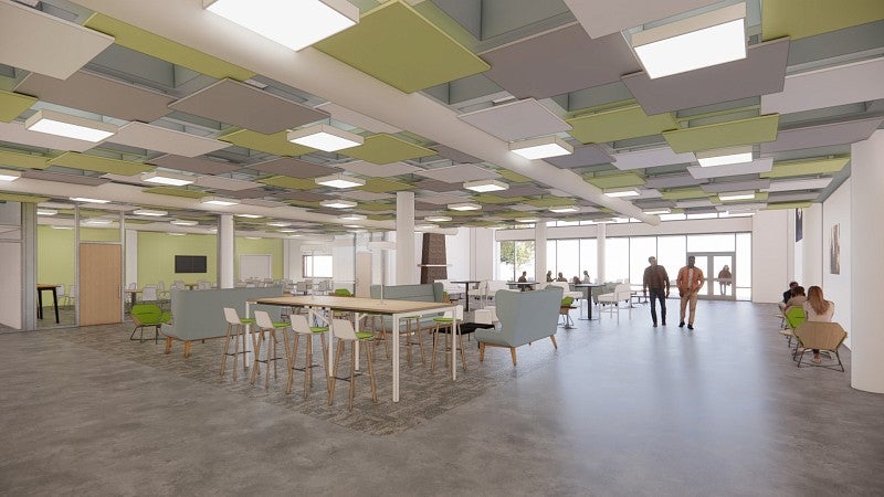 UO Portland Campus Center rendering dining room shows a bright and open space with a variety of seating and tables. The ceiling has a pattern of dropped tiles in tones of gray and light green. The back of the rendering show a wall of windows and doors that open to a patio. 