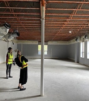 UO employees in construction vests and hard hats look up at the roof of the Sports Product management space during early renovations. The ceiling is open to the beams above. During renovation, it was discovered that the windows in the room had been covered at the top and now will be the full size. 